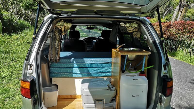 Tailgate open on the FBE338 campervan, showing the kitchen unit with sink, portable toilet and water container