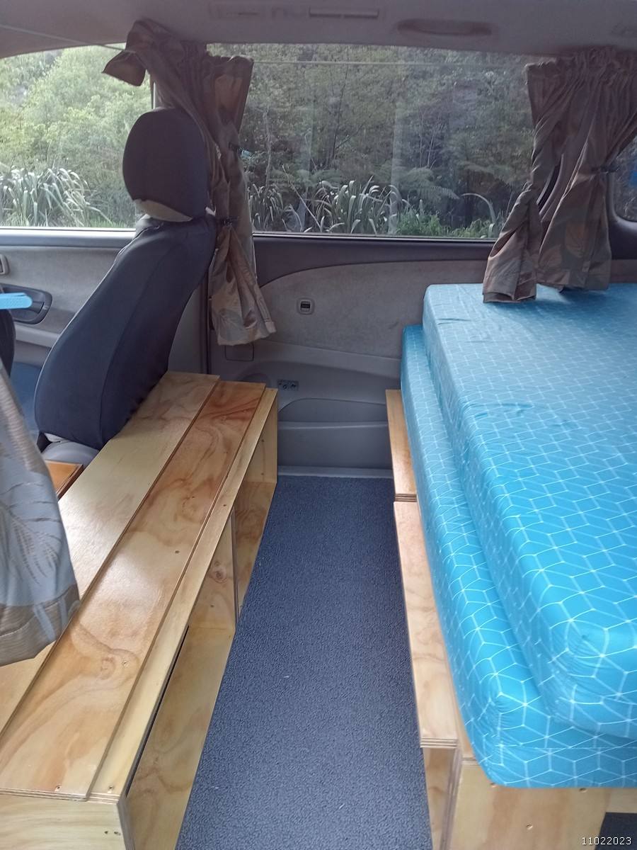 Inside the GRH325 campervan, bed on one side and the plywood bench seat opposite