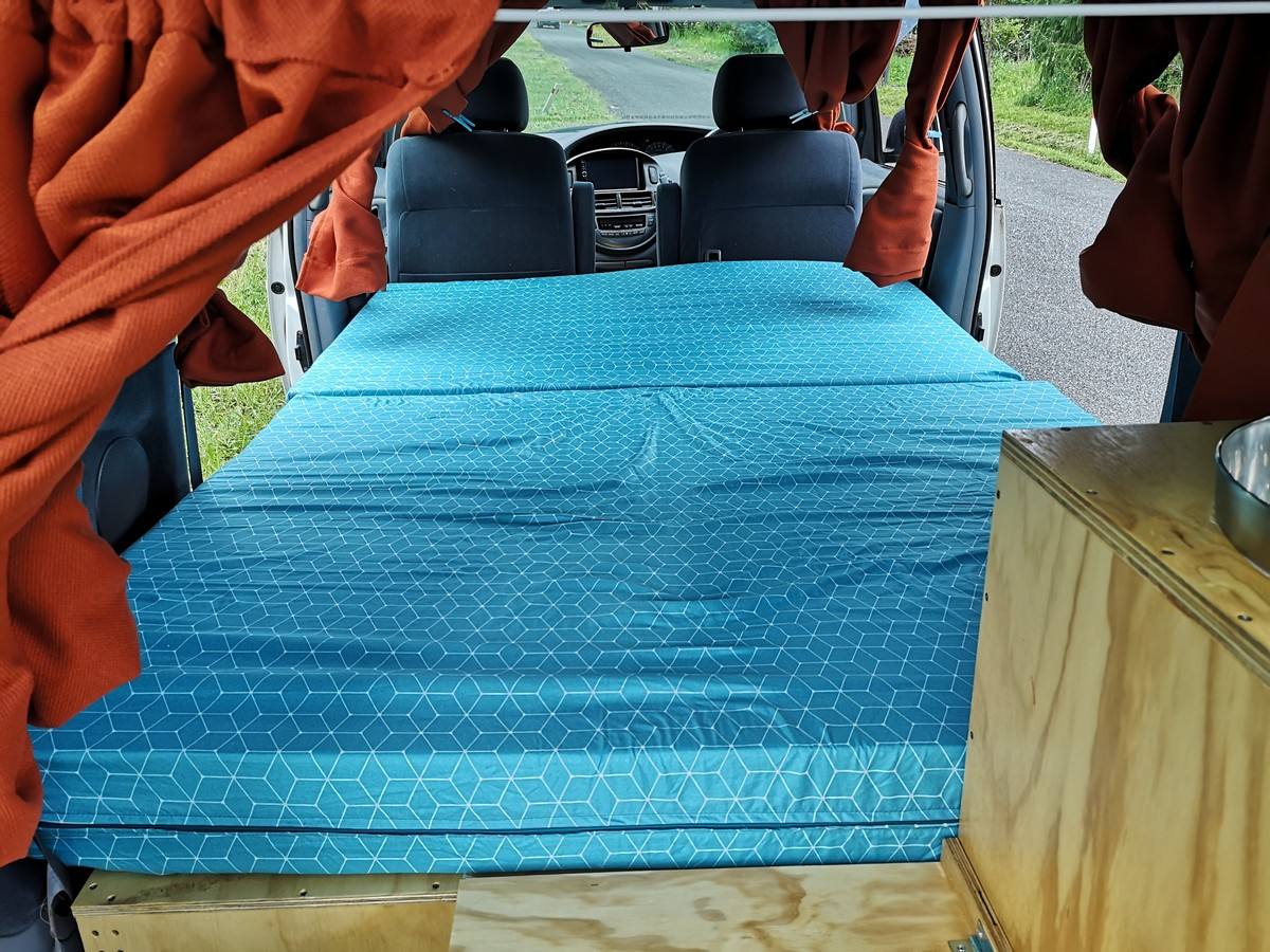 Inside the HDP33 campervan looking forward over the made-up bed to the front seats, sink unit on the right
