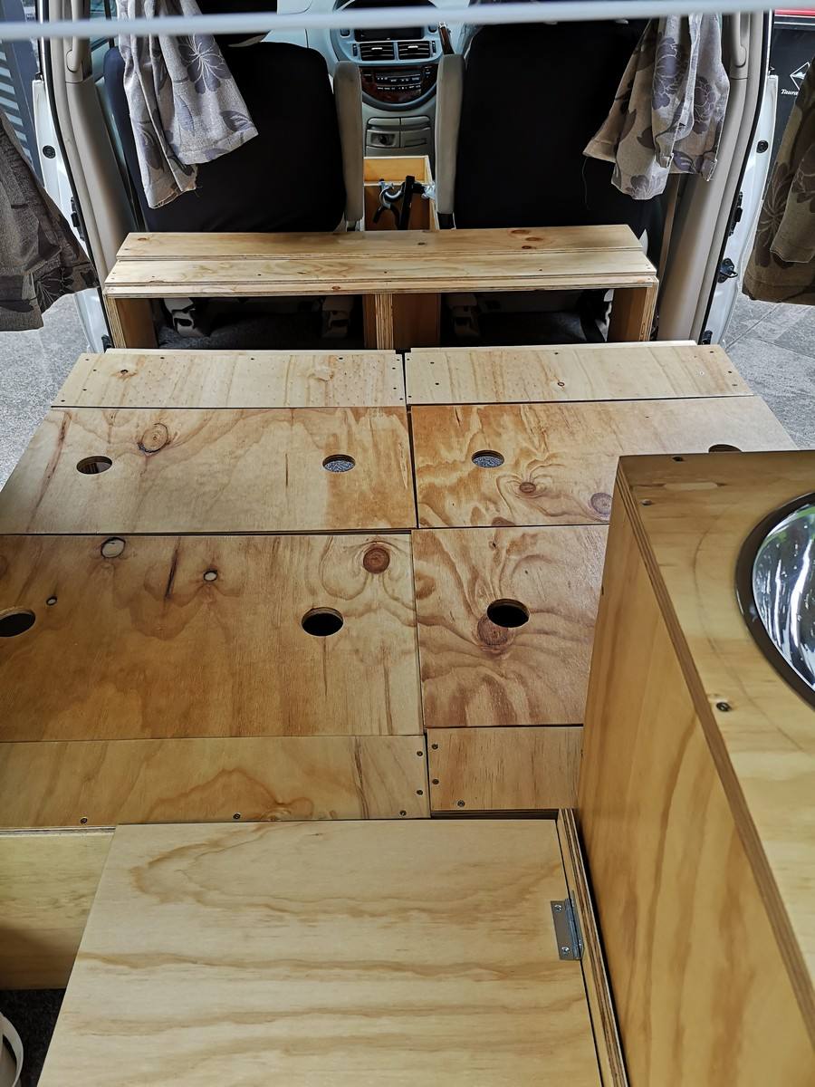 Plywood bed base of the KZR927 campervan laid out flat, with the bench across the back of the front seats