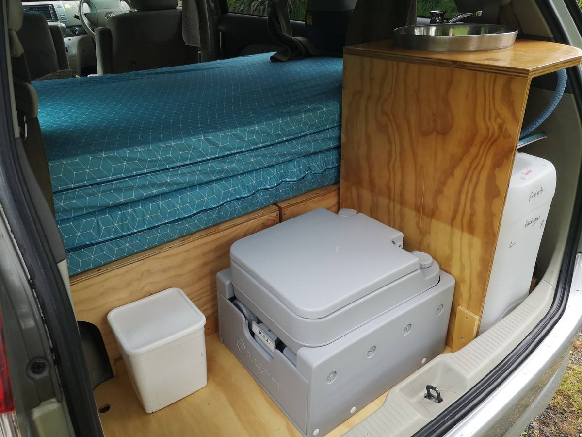 Portable toilet and chilly bin stowed under the sink unit in the JNQ545 campervan