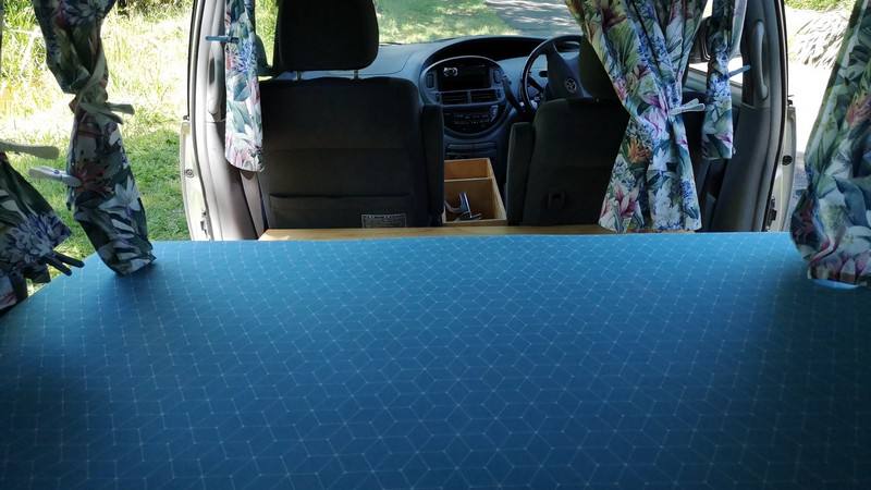 Inside the FYC899 campervan, bed made up looking forward to the front seats and dashboard