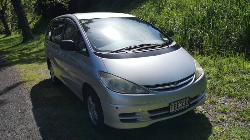 Front three-quarter view of the silver Toyota Estima campervan, registration FBE338, parked in dappled shade