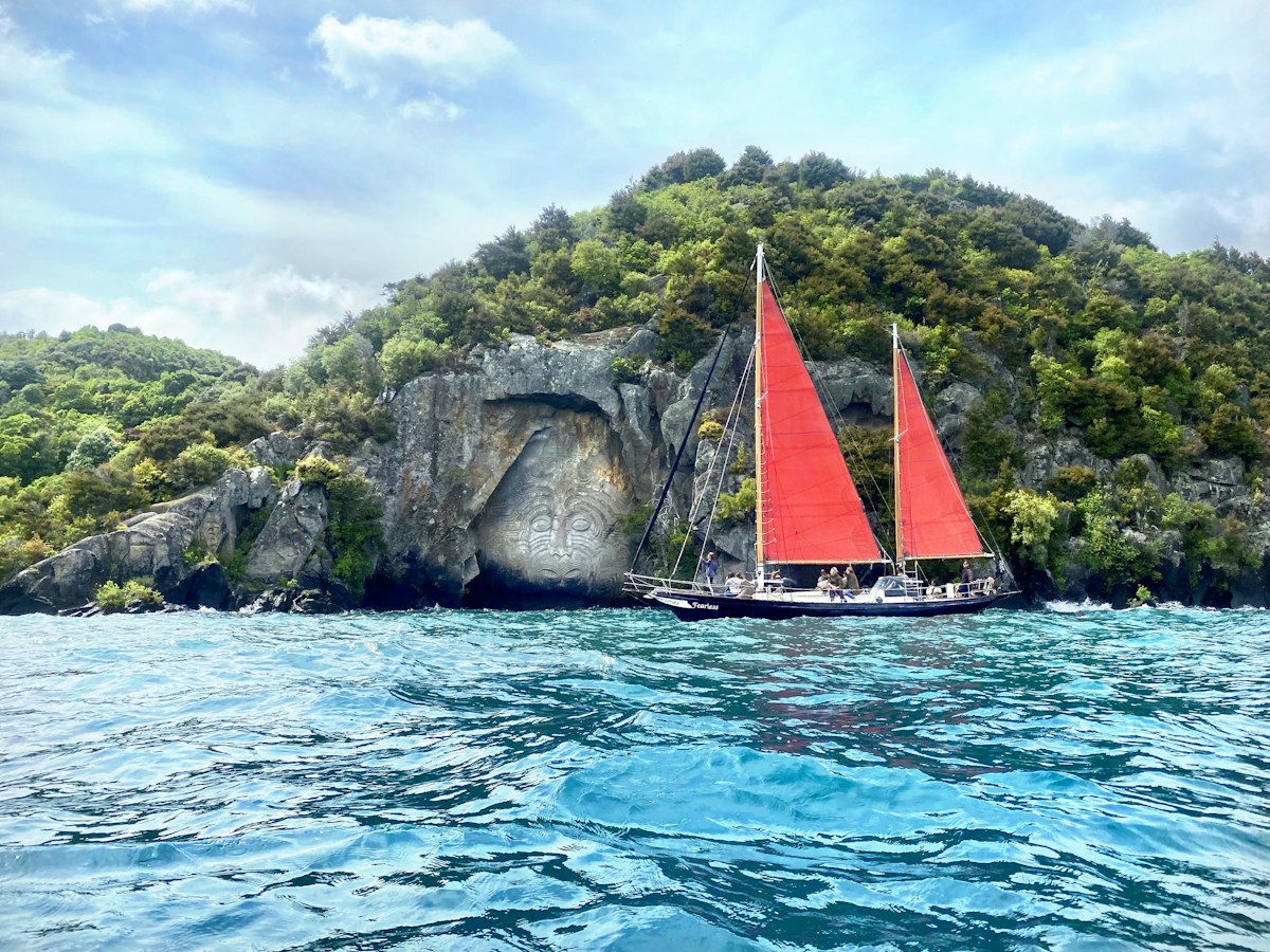 Red-sailed boat by the Ngātoroirangi Mine Bay rock carvings, Lake Taupō