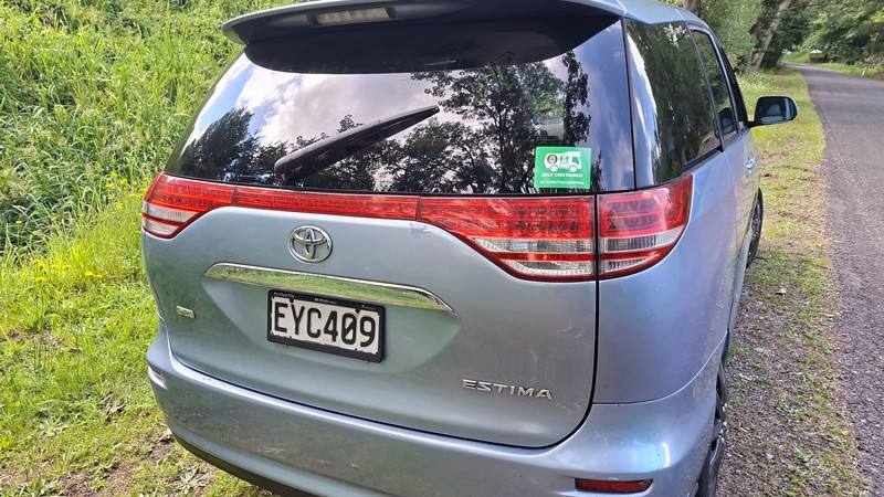 Back of the blue EYC409 Toyota Estima campervan, registration plate and self-contained sticker
