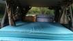 Inside the FAC789 Toyota Estima campervan, looking over the made-up double bed to the sink unit and the rear seats