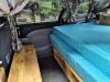Side door open on the JTQ214 campervan, bed made up with the timber bench alongside