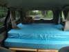 Inside the JNQ545 campervan, double bed made up looking out through the rear window