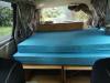 Inside the KBZ76 campervan, double bed made up looking forward to the sink unit and the cab