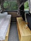 Inside the KZR927 campervan, mattress on the plywood base with the timber bench along the other side