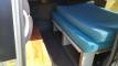 Side door open on the FBE338 campervan, showing the bed on its plywood base above the open storage shelves