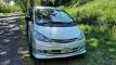 Front three-quarter view of the silver FYC899 Toyota Estima campervan on a country road