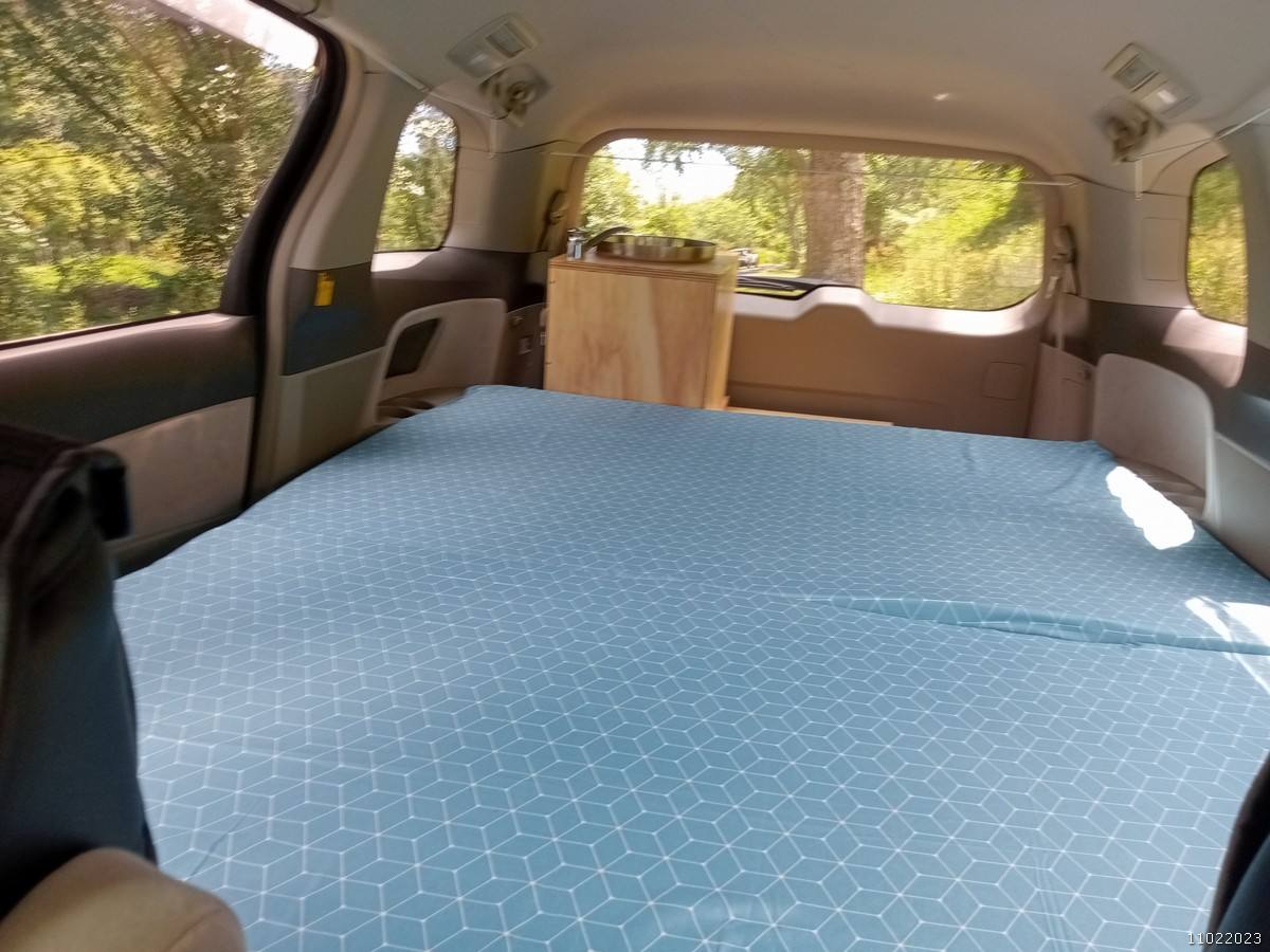 Inside the KHP570 campervan looking forward over the made-up bed to the kitchen unit