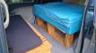 Inside the EYC409 campervan, bed on its timber frame with the bench seat and storage alongside