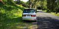 Back of the silver Toyota Estima campervan with registration GBB26, parked under trees