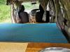 Inside the KBZ76 campervan, bed made up looking forward to the front seats, sink unit on the right