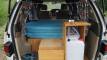 Tailgate open on the JBB773 campervan, showing the bed, sink unit and fresh water container