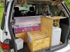 Tailgate open on the JDP67 campervan, showing the bed, kitchen unit with sink and the fresh water container