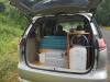 Tailgate open on the JNQ545 Toyota Estima campervan, bed, kitchen unit and water container packed inside