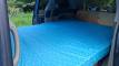 The EYC409 campervan's double bed made up across the van, sink unit at the far end