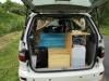 Tailgate open on the EZQ488 campervan, showing the bed, kitchen unit and fresh water container