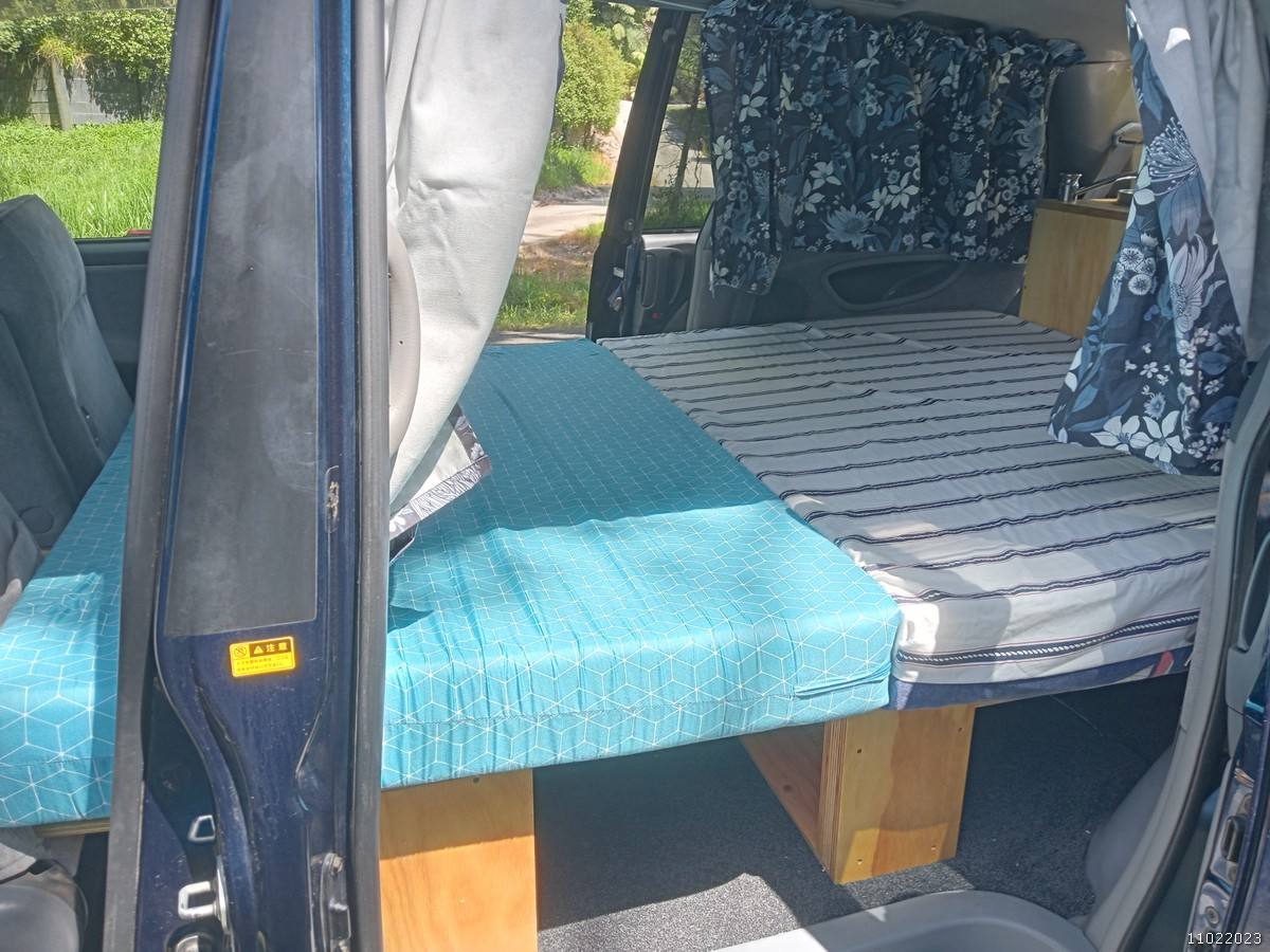Side door open on the FDK492 campervan, bed part made up on its plywood base