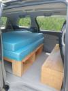 Side door open on the KHP570 campervan, bed on its plywood base with open storage underneath