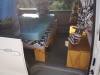 Side door open on the FQK81 campervan, bed made up on its plywood base with storage boxes alongside