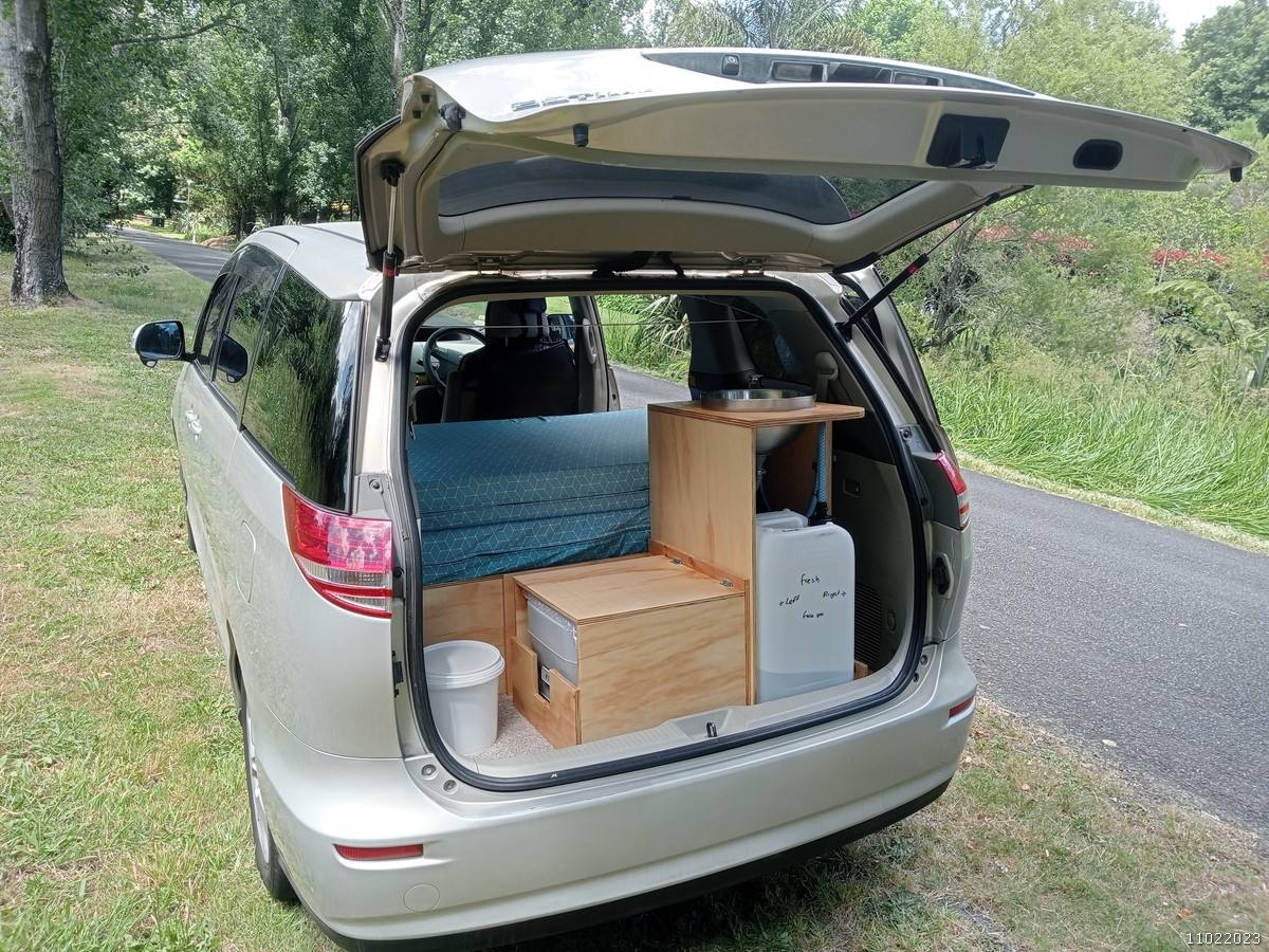 Tailgate open on the KHP570 campervan parked on a country road, kitchen unit and water container inside