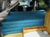 Inside the JTQ214 campervan looking forward over the made-up bed, portable toilet stowed alongside