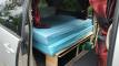 Side door open on the HMC107 campervan, double bed on its plywood base with storage underneath