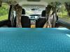 Inside the JTQ214 campervan, full-width bed made up looking forward to the front seats