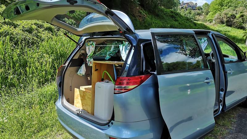 Tailgate open on the blue DJR846 campervan, showing the kitchen unit and the fresh water container