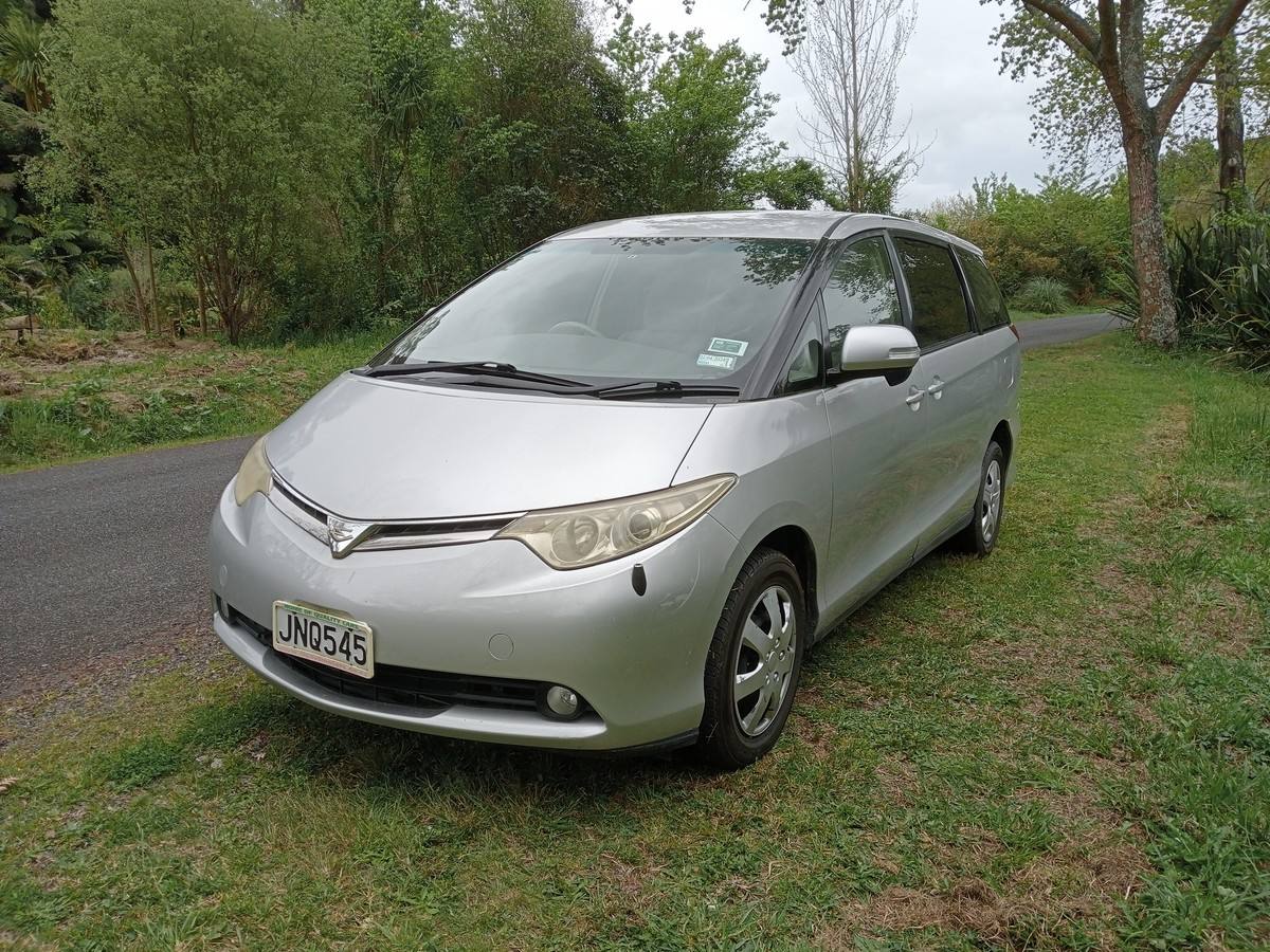 Front three-quarter view of the silver JNQ545 Toyota Estima campervan parked on a country road