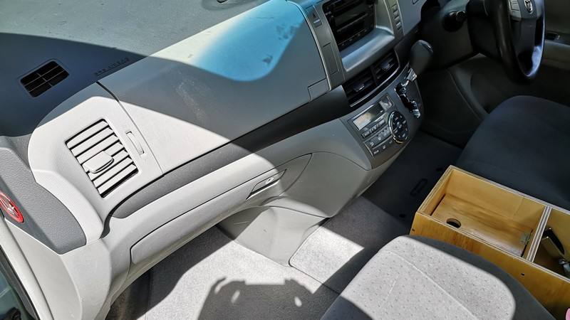 Dashboard of the DJR846 Toyota Estima seen from the passenger side, plywood console box between the seats