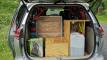 Tailgate open on the HMC107 campervan, packed with camping chairs, table, water container and the kitchen unit