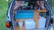 Tailgate open on the ERT416 campervan, showing the bed, portable toilet, sink unit and water container