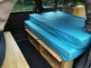 Bed on its plywood base in the EZQ488 campervan, with open storage shelves underneath