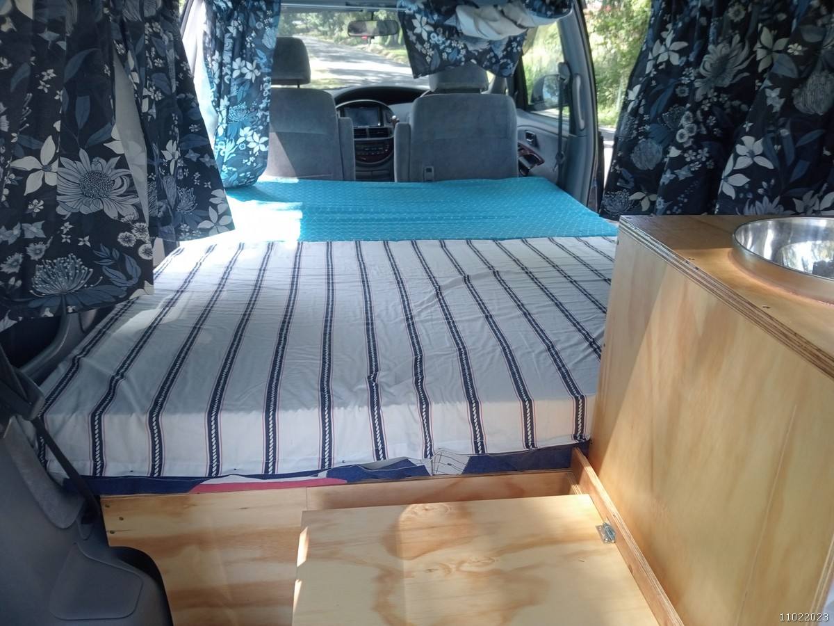 Inside the FDK492 campervan, bed made up looking forward to the front seats and dashboard