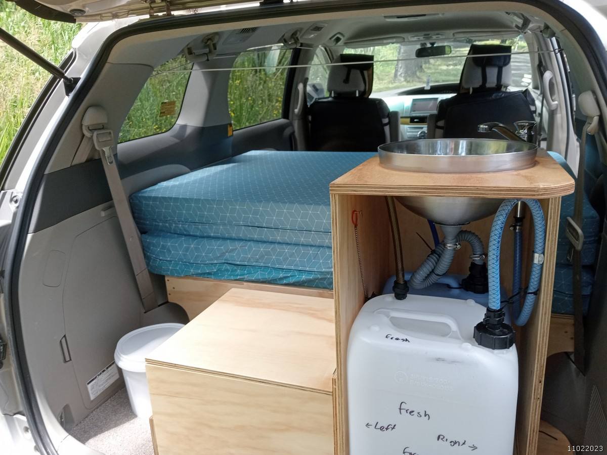 Tailgate open on the KHP570 campervan, showing the bed, sink unit and fresh water container