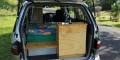 Tailgate open on the GBB26 campervan, showing the plywood kitchen unit with stainless sink beside the bed