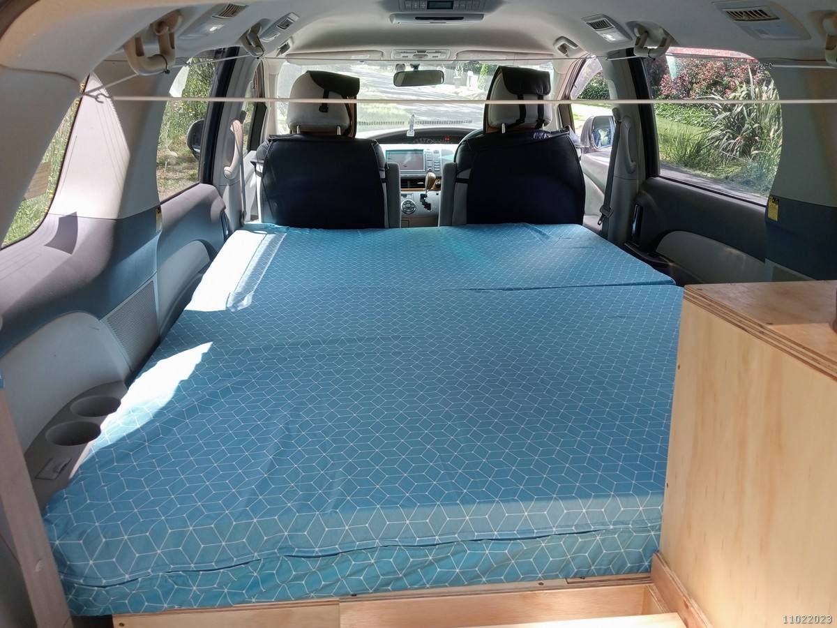 Inside the KHP570 campervan, full-width bed made up looking forward to the front seats