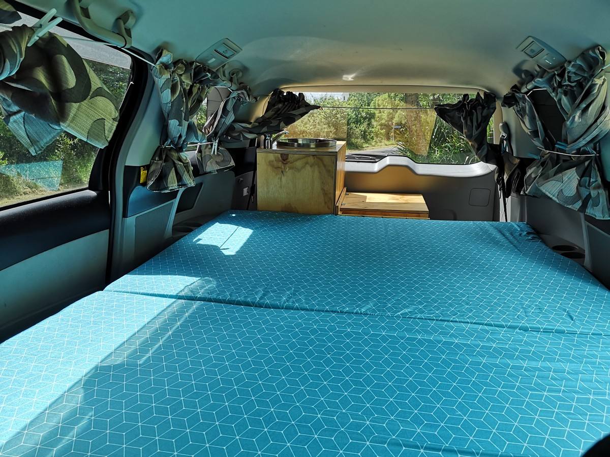 Looking forward across the JTQ214 campervan's bed to the sink unit and the cab
