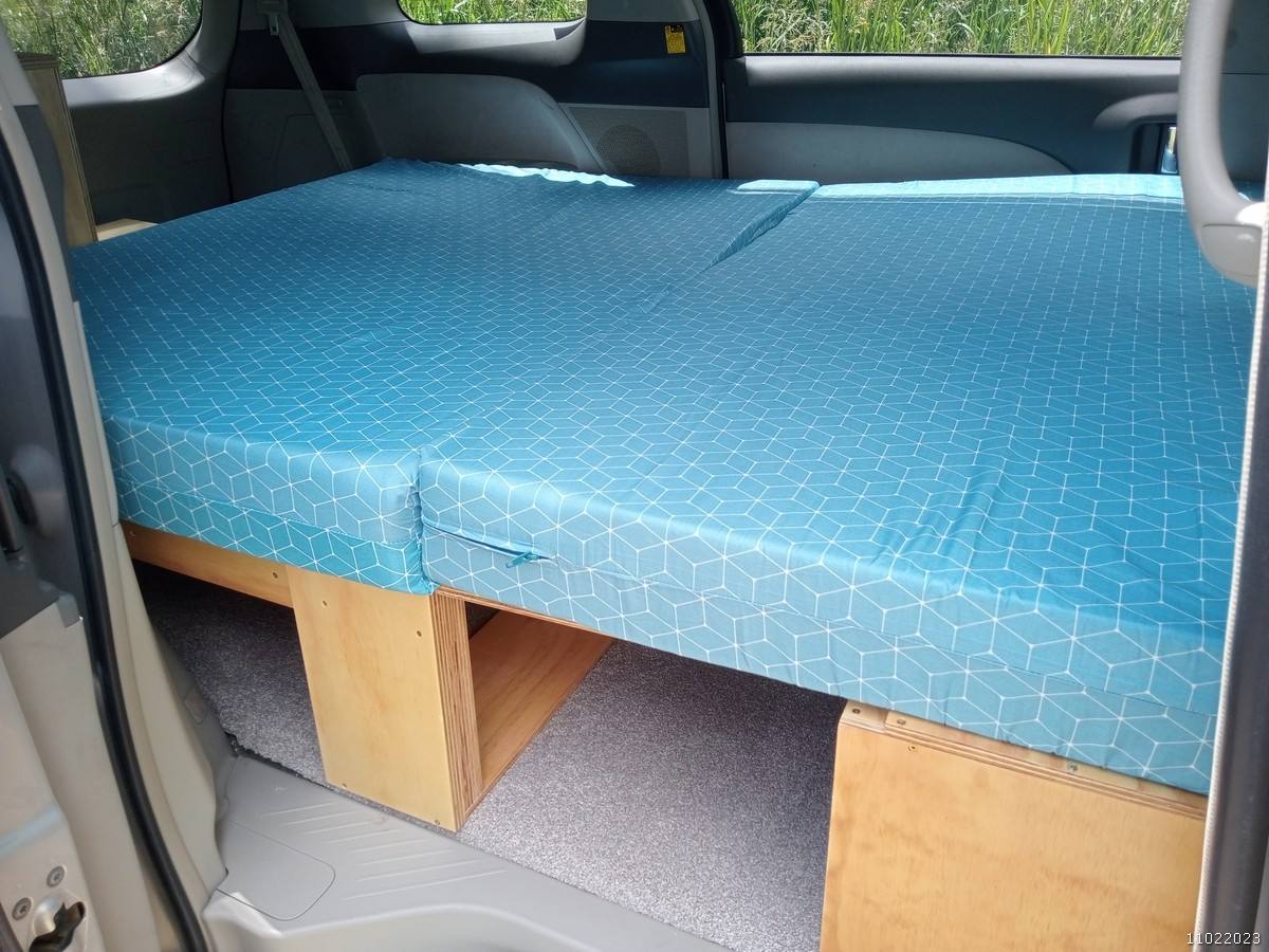 The KHP570 campervan's double bed made up across the van, storage boxes underneath