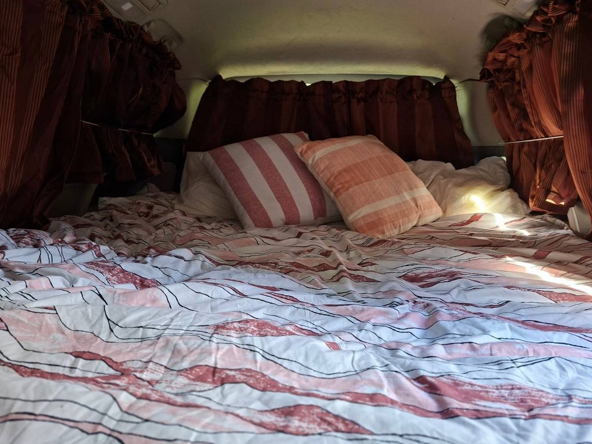 The JAK653 campervan's double bed made up with a duvet and pillows