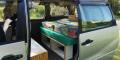 Inside the GBB26 Toyota Estima campervan through the open side door, bed and storage shelving