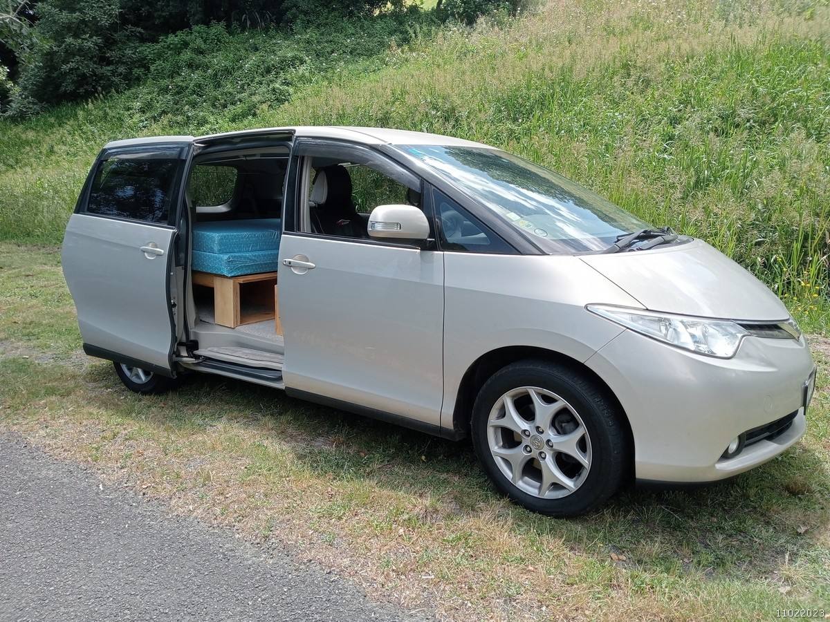 Side door open on the gold 2006 Toyota Estima campervan KHP570, bed and storage visible inside