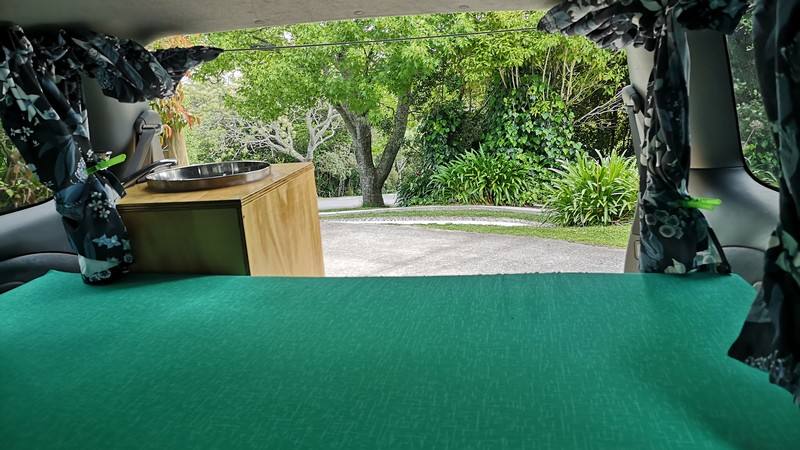 Inside the FDK492 campervan looking over the bed to the sink unit and out through the open tailgate