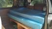 Inside the GQG541 campervan, bed made up on its timber base with storage underneath
