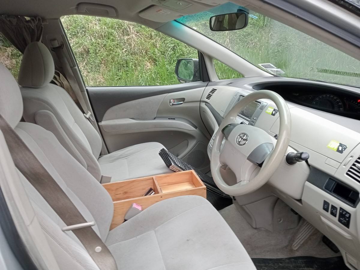 Front seats and dashboard of the JNQ545 Toyota Estima, plywood console box between the seats